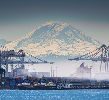 Shipping containers being unloaded with Mount Rainier in the background